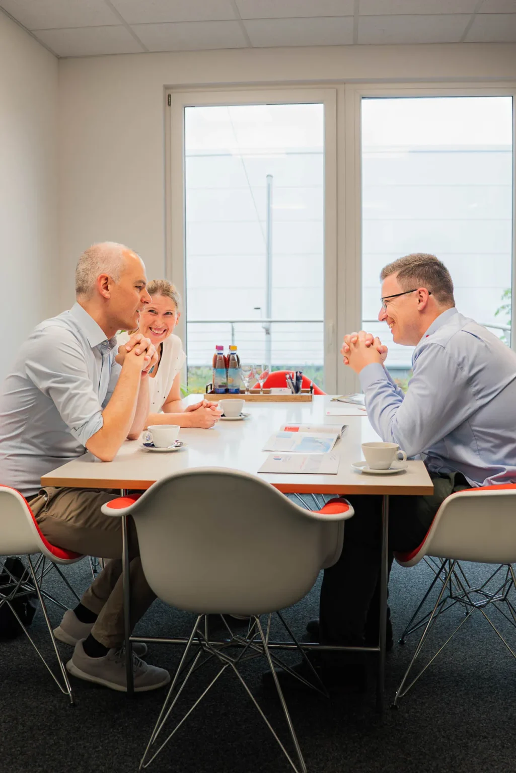 Kunden und Berater lachen gemeinsam am Besprechungstisch